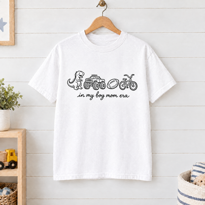 White In My Boy Mom Era shirt on a wooden hanger in a kids playroom
