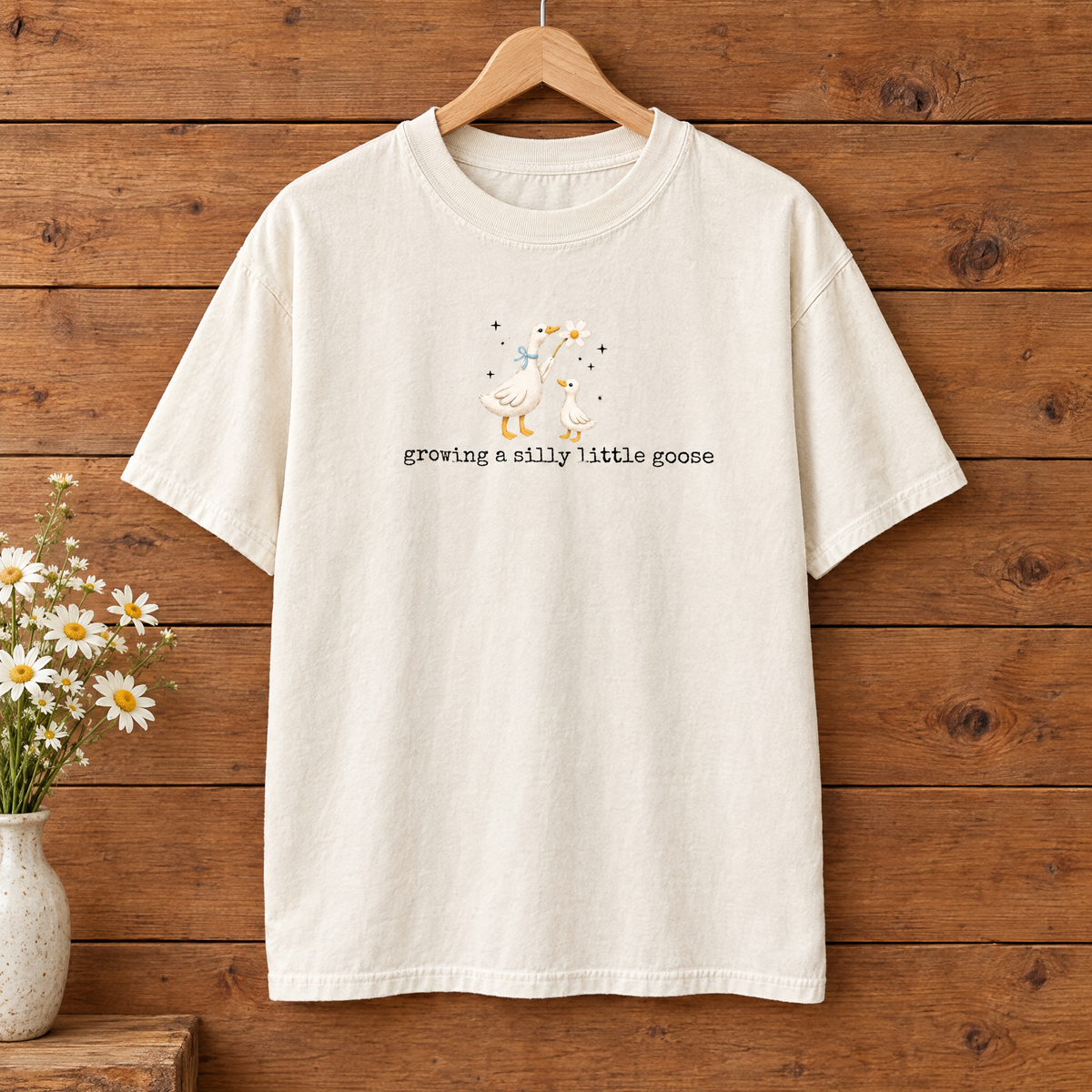 Growing a Silly Little Goose Comfort Colors shirt in Natural Ivory on a wooden hanger