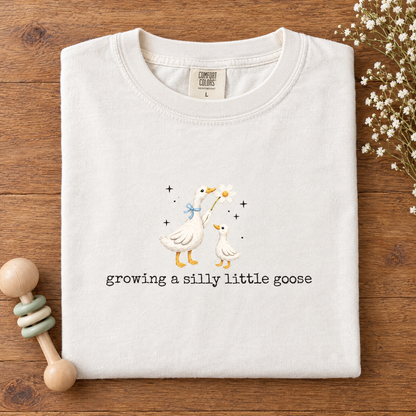 Cute maternity goose tee in White, folded with a wooden baby rattle