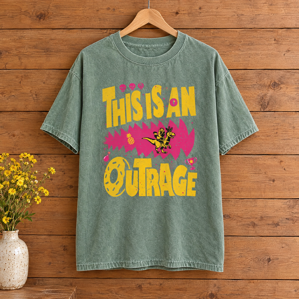 This Is An Outrage Comfort Colors shirt in Light Green on a wooden hanger