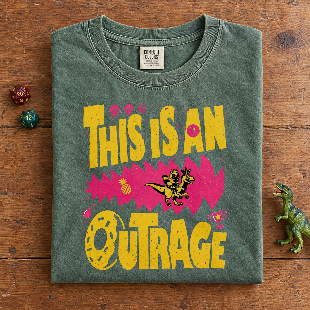 Funny bookish tee in Moss, folded with dice and a toy dinosaur